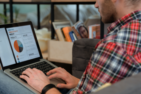 A man sitting in a chair reviewing data on a laptop