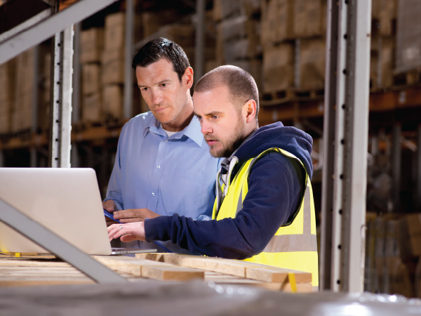 Two men looking at a computer in a warehouse