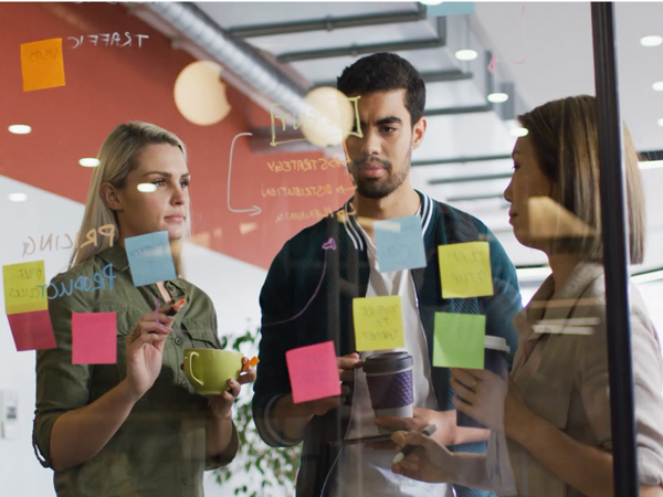 A group of colleagues writing on glass board and discussing 