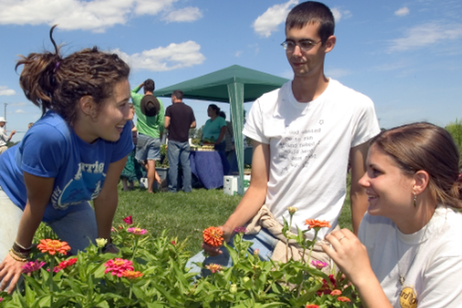 Three people picking and smelling flowers.