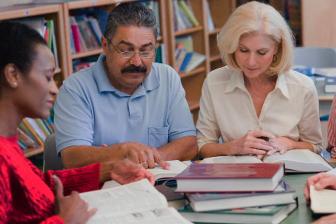 A group of 5 people sitting around a table reviewing documents.