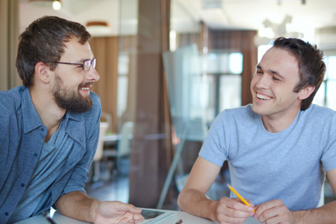 Two men sitting at a table having a discussion.