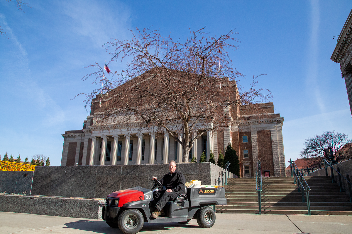 Todd Knowler on a Landcare vehicle in front of Northrop Auditorium